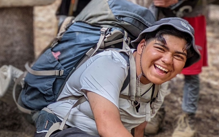 a student wearing a backpack laughs on a outward bound backpacking trip